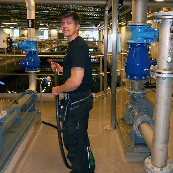 A man is standing in a treatment plant servicing a pump motor.
